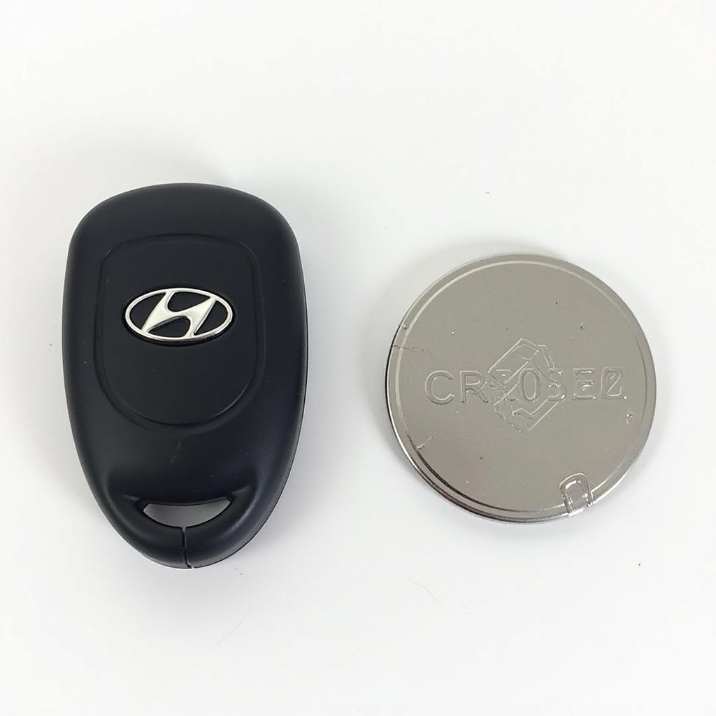 Hyundai Tucson 2019 key fob with a CR2032 battery placed next to it for size comparison.