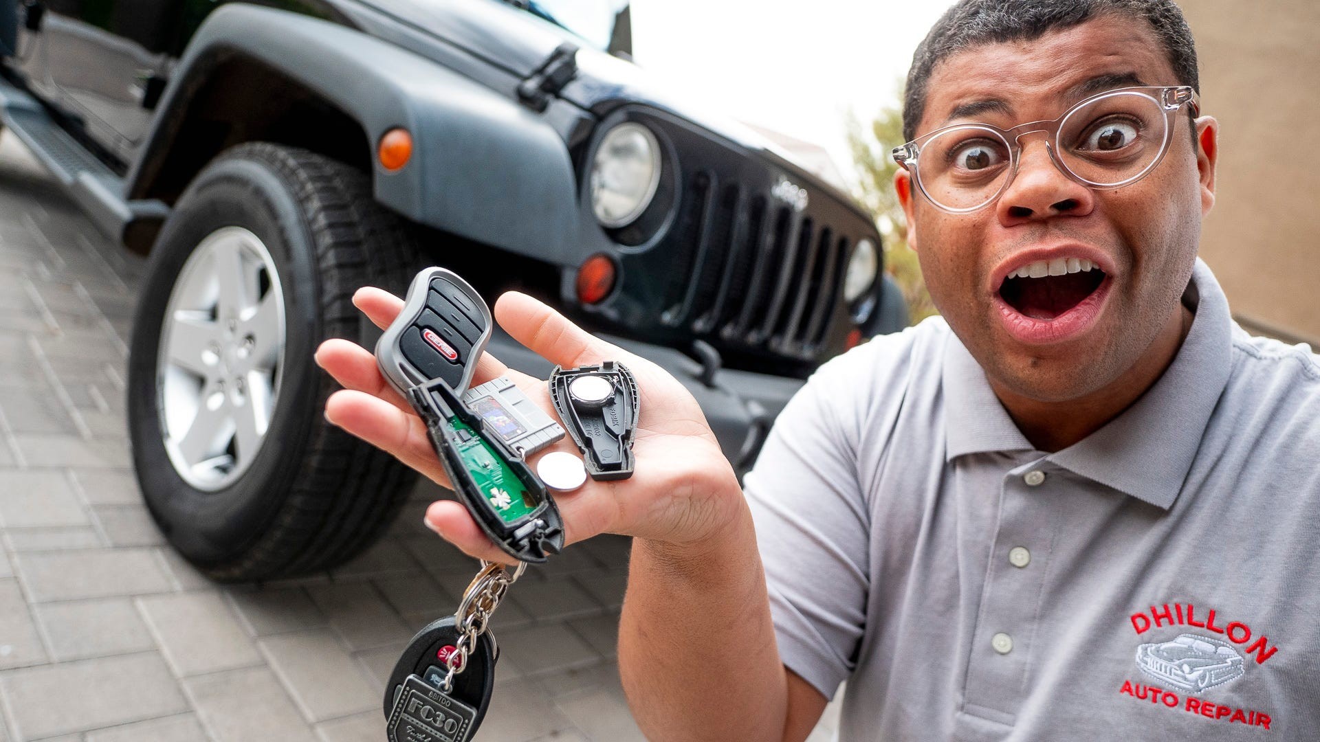 Close up of hand holding car key fob and screwdriver to open battery compartment