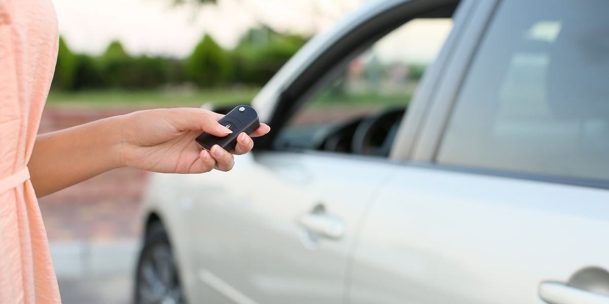 Close-up of hands programming a car key fob using a car manual