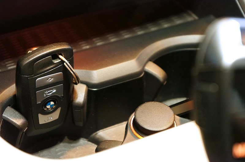 BMW key fob inserted into a car cupholder as a makeshift holder solution