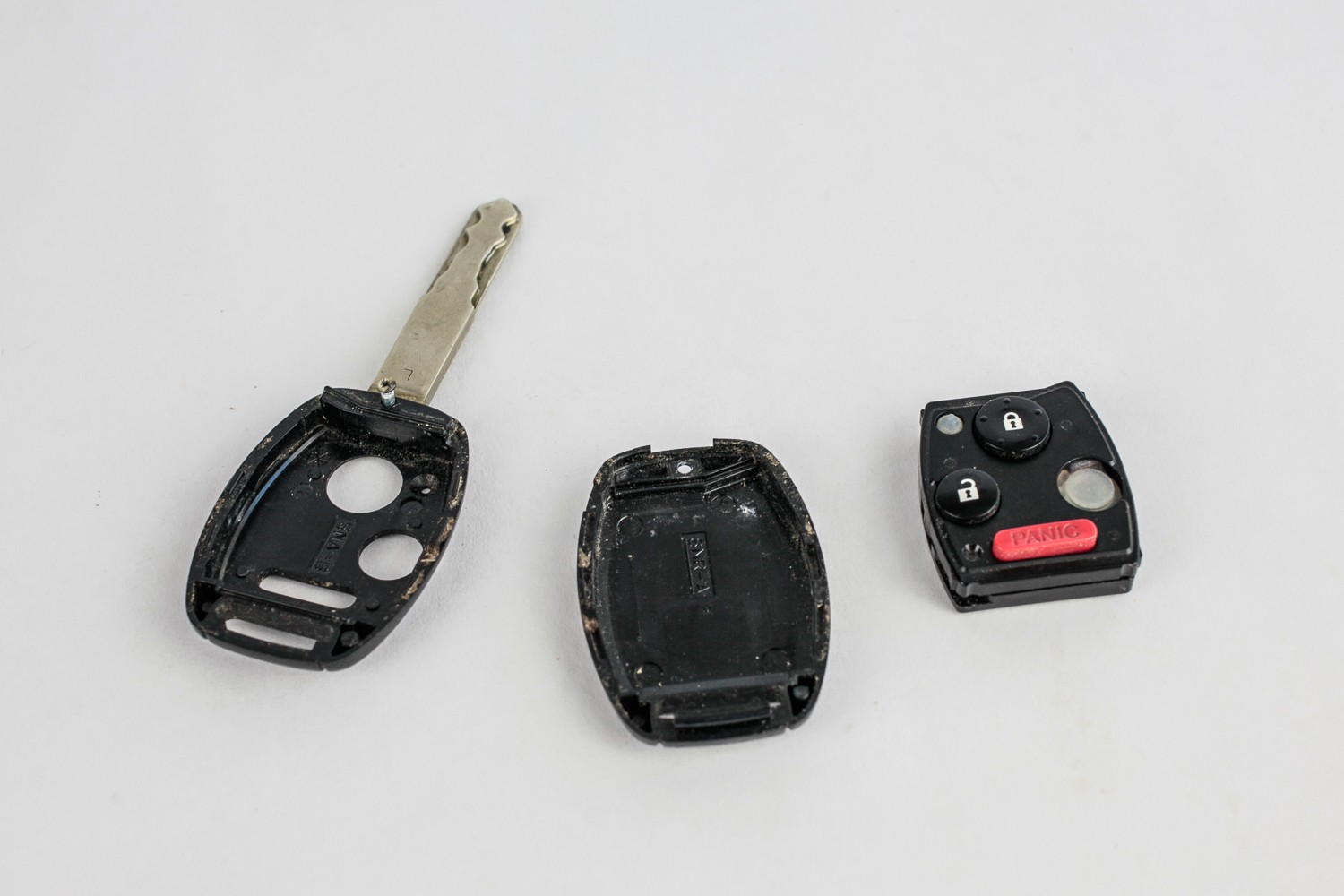 Disassembled components of a car key fob, revealing the internal circuit board and battery housing.