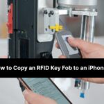 Close up of a person using an iphone to scan an rfid key fob, demonstrating the process of copying a key fob to a phone.