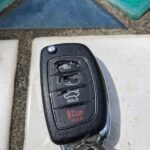 Close-up of a severely cracked and disintegrated Hyundai key fob case, showing worn-out button area.